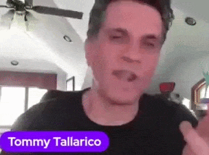 A Man In A Black Shirt With The Name Tommy Tallarico On A Purple Sticker GIF