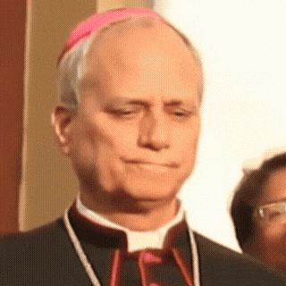 A Man In A Black Suit And A Pink Hat Looks Down GIF