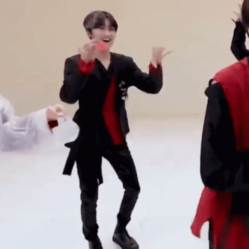 A Man In A Black Suit And Red Shirt Is Dancing On A White Floor While Holding A Donut . GIF