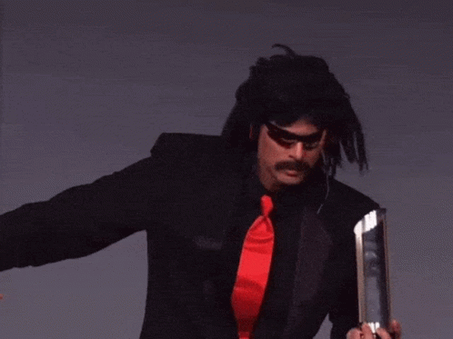 A Man In A Black Suit And Red Tie Is Holding A Trophy With The Words Two Steps Behind Him GIF