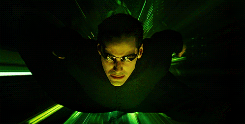 A Man In A Black Suit And Sunglasses Is Flying Through A Green Light GIF