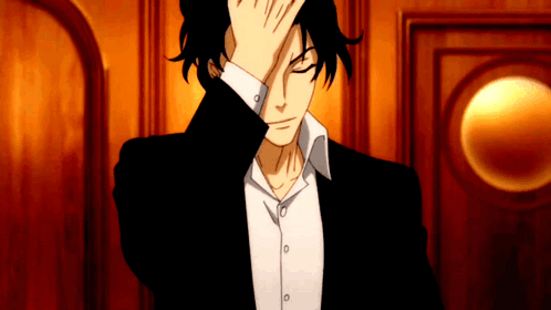 A Man In A Black Suit And White Shirt Is Covering His Face With His Hand GIF
