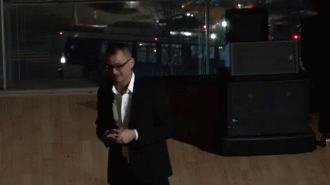 A Man In A Black Suit And White Shirt Is Giving The Peace Sign GIF