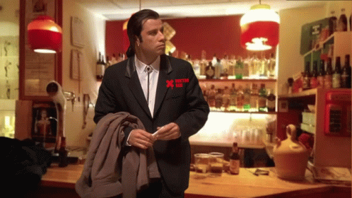a man in a black suit has a red x on his pocket