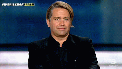 A Man In A Black Suit Is Sitting In Front Of A Screen That Says Viperissimo Trash GIF
