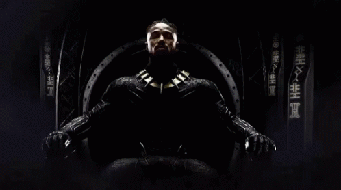 A Man In A Black Suit Is Sitting On A Throne With Chinese Writing On The Wall Behind Him GIF