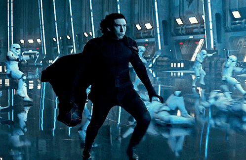 A Man In A Black Suit Is Standing In Front Of A Group Of Stormtroopers GIF