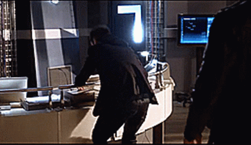 a man in a black suit is standing in front of a monitor