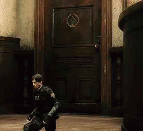 A Man In A Black Suit Is Standing In Front Of A Wooden Door In A Room . GIF
