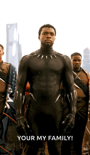 A Man In A Black Suit Stands In Front Of A Group Of Men With The Words Your My Family Below Him GIF