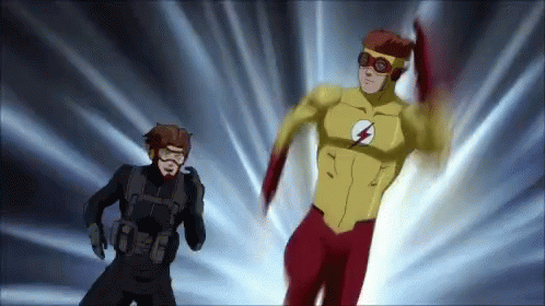 A Man In A Black Suit Stands Next To A Man In A Yellow And Red Superhero Costume . GIF