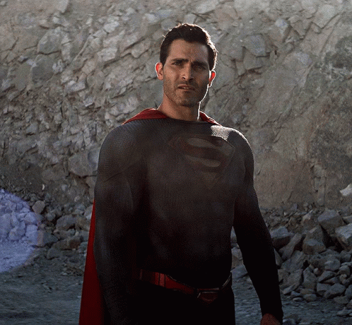 A Man In A Black Superman Costume With A Red Cape GIF