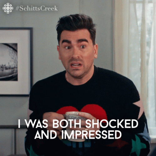 A Man In A Black Sweater Is Holding A Cup And Says I Was Both Shocked And Impressed GIF