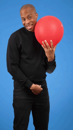 A Man In A Black Sweater Is Holding A Red Balloon In Front Of His Face GIF
