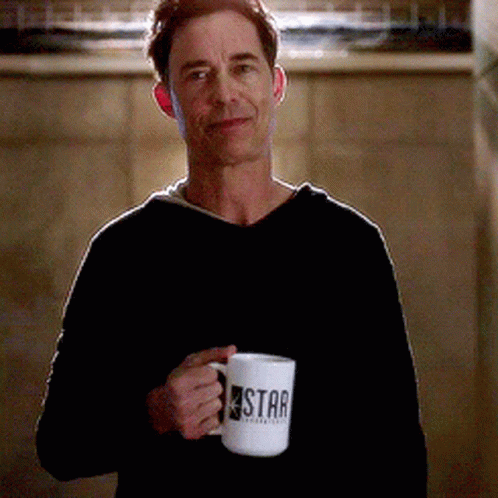A Man In A Black Sweater Is Holding A Star Mug GIF