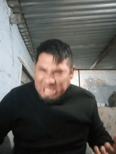 A Man In A Black Sweater Is Making A Funny Face GIF