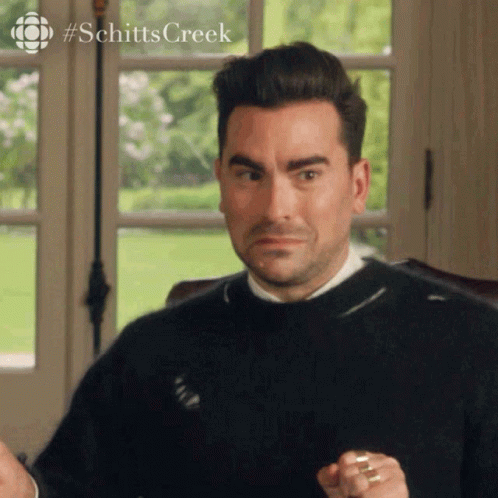 A Man In A Black Sweater Is Sitting In Front Of A Window And Making A Face . GIF