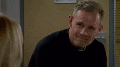 a man in a black sweater is smiling while looking at a woman
