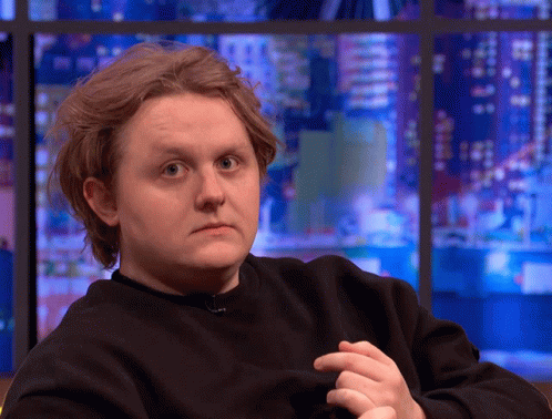A Man In A Black Sweater Looks At The Camera GIF