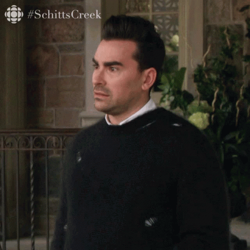 A Man In A Black Sweater Says Okay In Front Of A Brick Building GIF