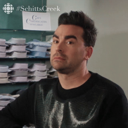 A Man In A Black Sweater Stands In Front Of A Sign That Says Gift Certificates Available GIF