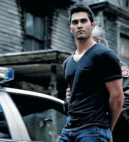 A Man In A Black T-Shirt Is Being Arrested By A Police Officer GIF