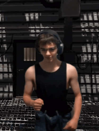 A Man In A Black Tank Top And Headphones Is Running GIF