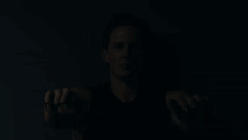 A Man In A Black Tank Top Holds His Hands Out GIF