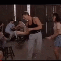 A Man In A Black Tank Top Is Dancing In Front Of A Crowd GIF