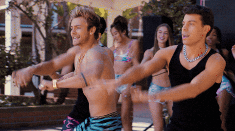 a man in a black tank top is dancing with a group of people