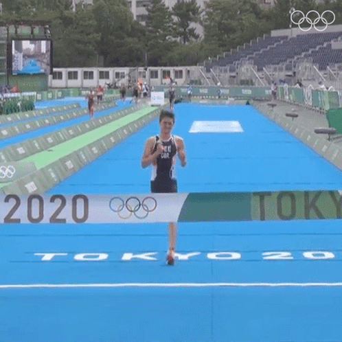 A Man In A Black Tank Top Is Running On A Blue Track With The Number 20 On It GIF