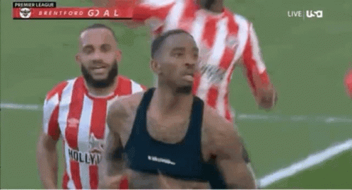 A Man In A Black Tank Top Is Running On A Soccer Field With Other Players . GIF