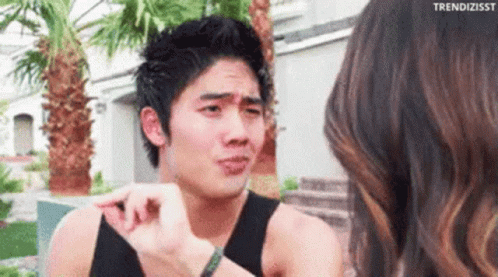 A Man In A Black Tank Top Is Talking To A Woman . GIF