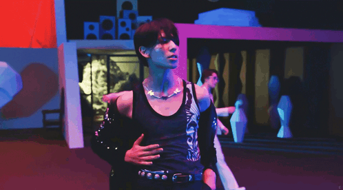 A Man In A Black Tank Top With A Necklace Around His Neck GIF