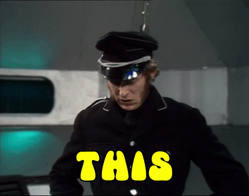 A Man In A Black Uniform Is Standing In Front Of A Yellow Sign That Says This GIF