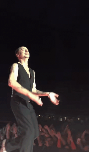 A Man In A Black Vest Is Dancing On A Stage GIF