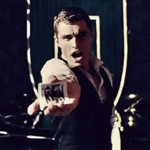 A Man In A Black Vest Is Holding A Piece Of Paper In His Hand GIF
