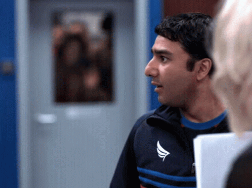 A Man In A Blue And Black Jacket With A White Wing On The Front GIF