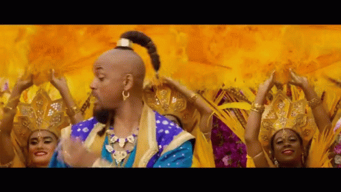 A Man In A Blue And Gold Costume Is Surrounded By Women In Yellow Dresses GIF