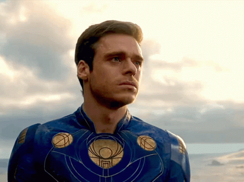 A Man In A Blue And Gold Superhero Costume Looks At The Sky GIF