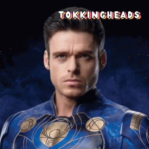 A Man In A Blue And Gold Superhero Costume With The Words Tokingheads Above Him GIF