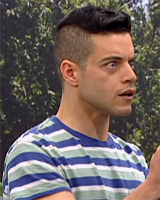 A Man In A Blue And Green Striped Shirt Looks To The Side GIF