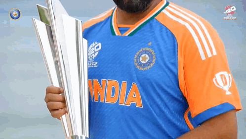 A Man In A Blue And Orange India Jersey Holds A Silver Trophy GIF
