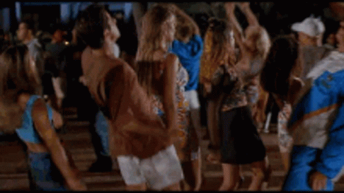 a man in a blue and white jacket is dancing in a crowd of people .