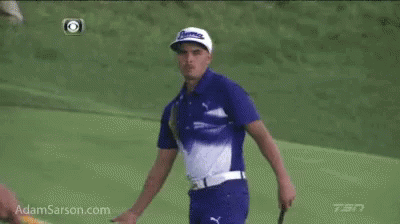 A Man In A Blue And White Shirt Is Standing On A Golf Course GIF