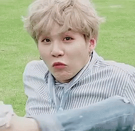 A Man In A Blue And White Striped Shirt Is Sitting In The Grass With A Dog . GIF