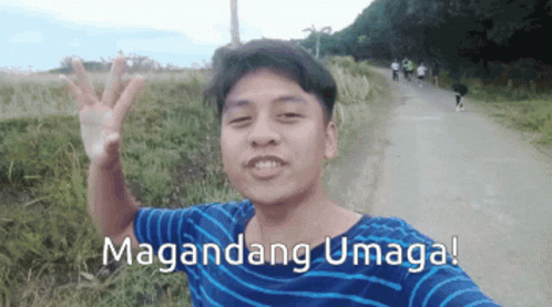 A Man In A Blue And White Striped Shirt Is Waving In Front Of A Sign That Says Maganda GIF