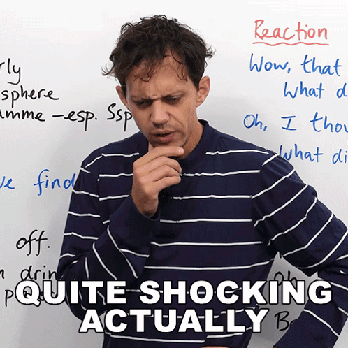A Man In A Blue And White Striped Shirt Stands In Front Of A Whiteboard That Says Reaction GIF