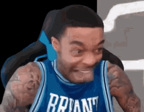 A Man In A Blue Basketball Jersey Is Making A Funny Face . GIF