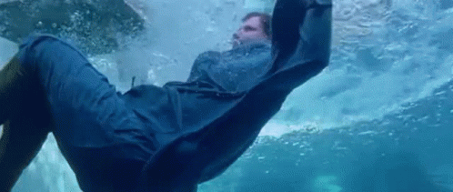 A Man In A Blue Coat Is Swimming In The Water . GIF